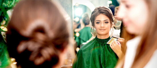 Fototapeta na wymiar Make-up artist doing makeup for young beautiful bride applying wedding makeup in a beauty salon