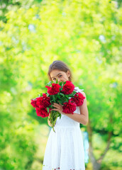 Little cute girl with peony flowers. Child wearing white dress playing in a summer garden. Kids gardening. Children play outdoors. Toddler kid with flower bouquet for birthday or mother s day.