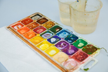 box with paints and a glass for water