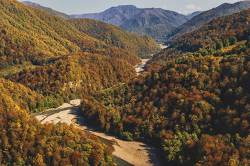 A colorful landscape with mountains, a curved river, an autumn forest. Mountain valley. Autumn mountain landscape with a river.