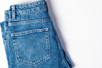 Blue cotton jeans on a white concrete, stone or slate background. The texture of the denim background for the design. top view with space to copy. Jeans advertising. Casual fashionable outfit.