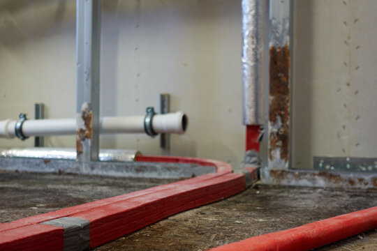 Red Isolated Water Pipe Causing Brown Mold Stains On Wood Floor. Unconnected Sewage Pipe In The Background. Insurance Claim.