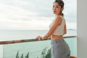 Fototapeta premium Beautiful Asian woman enjoy looking the sea view from the balcony of the hotel.