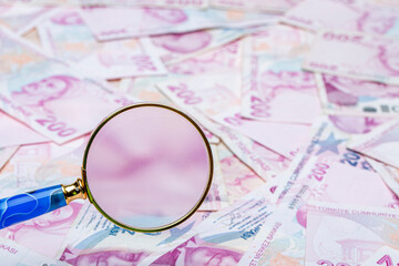 Close up two hundred turkish liras with magnifying glass. Saving money, finance, business, goal...