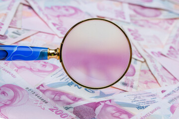 Close up two hundred turkish liras with magnifying glass. Saving money, finance, business, goal...