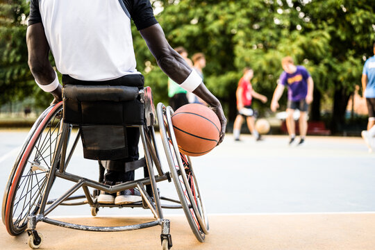 african american basketball player in wheelchair waiting to play on open air ground, concept of accessibility to sports for disabled athlete, social inclusion