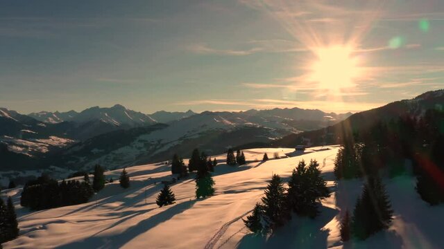 Golden Sun Light at Sunset in Mountains. Beautiful Sunny evening. Aerial view of Winter Mountains. Beautiful Winter Landscape. Flying above Snowy Alps mountains.