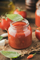Fototapeta na wymiar Jar of home made classic Tomato sauce on wooden table