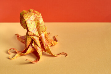 Origami octopus model on a yellow and orange background. Origami figure on a paper texture surface. World origami day