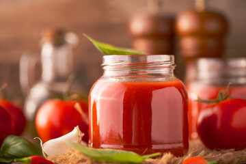Fototapeta na wymiar Jar of home made classic Tomato sauce on wooden table