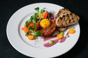 Beef tartare garnished with sauces with herbs and served with croutons.