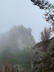 Cross on top of a mountain, on a rock in the fog