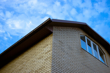 Corner of a tall brick house with a window in the attic