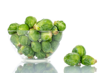 Organic ripe brussels sprouts in a glass bowl, close-up, isolated on white.