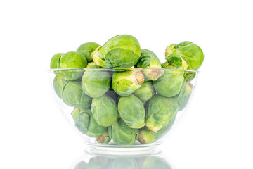 Organic ripe brussels sprouts in a glass bowl, close-up, isolated on white.