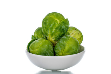 Organic ripe brussels sprouts with white saucer, close-up, isolated on white.