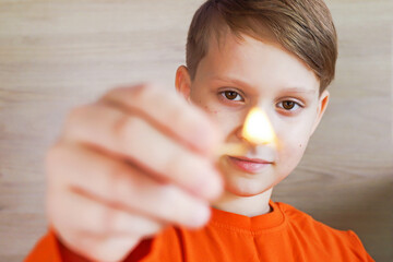 A child boy holding a lighted match in his hands is very dangerous