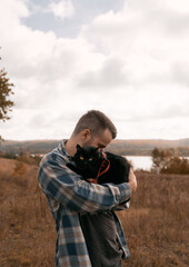 Man with a black cat on his shoulder. Bearded man wearing check shirt outdoor with his favorite domestic pet.