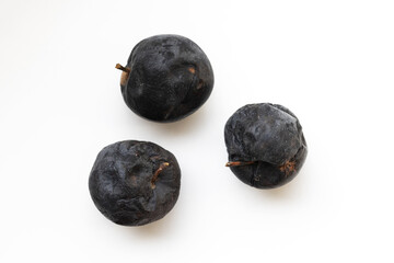 Three black rotten apples on the white background. Shot from above. Soft side light
