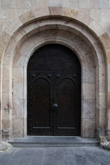 Ancient rusty black arch shape metal doors to a church. Shot in Georgia.