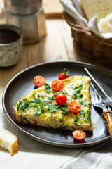 Breakfast of omelet with vegetables, herbs and cheese, served with bread and coffee.