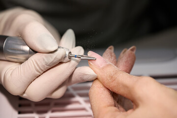 Woman doing manicure for herself with the nail drill. High quality photo