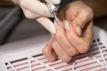 Woman doing manicure for herself with the nail drill. High quality photo
