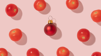 Creative composition pattern with fresh cherry tomatoes and red Christmas bauble on bright pink background.