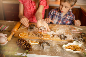 Brother and sister in the home kitchen bake cookies. The girl shows cookies. Defocus background