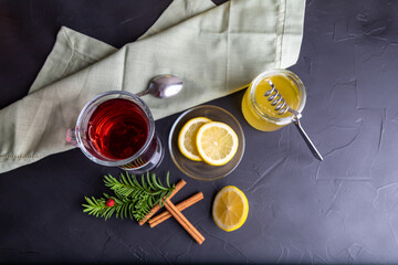 Hot fruit tea with lemon and honey on the dark surface.