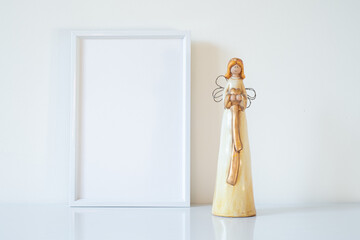 Vertical white blank frame mockup with porcelain Christmas angels. Wedding scene. Christmas, Valentine's day concept. Copy space.