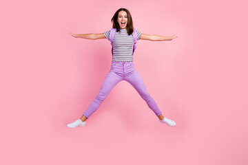 Photo of excited funky young lady wear striped outfit backpack smiling jumping high like star isolated pink color background