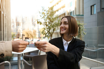 Attractive young fashionable brunette woman hands over a plastic credit card for payment.