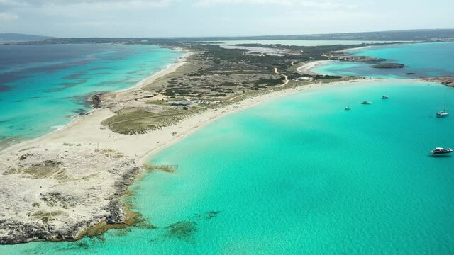 Illetes beach in Formentera, turquoise waters and white sand. Boats and yachts moored off its shores in summer. Drone footage.