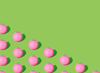 Creative pattern made of New Year's glittery balls of pink color on a green background. Holiday minimal aesthetic idea. Christmas composition.
