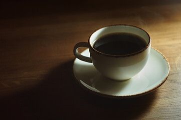 a cup of black coffee on a wooden table