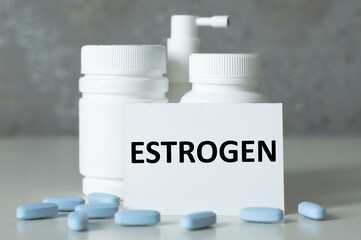 a bottles for pills, scattered pills in the foreground and a card with the inscription ESTROGEN. Medical concept