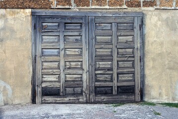 one closed big old gray wooden door on a brown concrete wall in the street