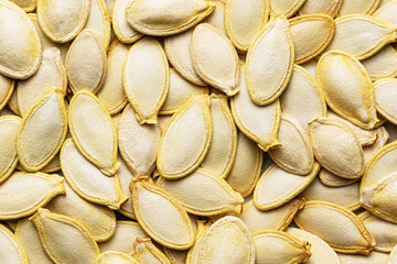 Pumpkin seeds background. Dried seeds piled in a heap. Close up photo.