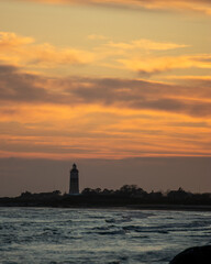 sunset over the sea with a lighthouse