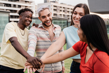 Young diverse group of people celebrating together stacking hands outdoor - Focus on gay man...