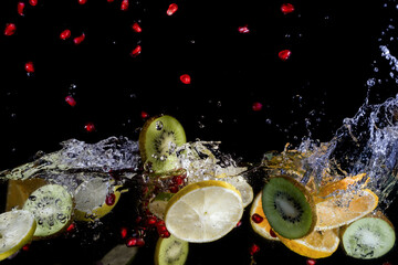 Naklejka na ściany i meble Bright juicy fruits on a dark background with a spectacular splash in high definition