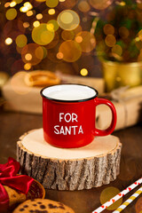 Red cup of milk and cookies for Santa Claus. Christmas treat for Santa vertical photo