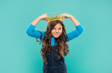 unpleasant teen girl with curly hair wear crown on blue background, selfishness