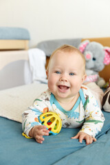 Baby Teether and Toys, Little baby playing with aToy in a Bed, Infant Child Growing First Tooth, Europe.