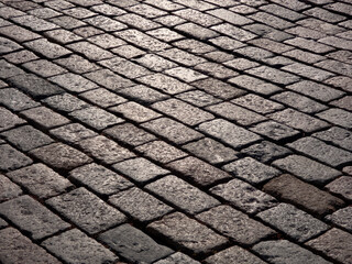 Gray granite cobblestone of the old city glistens in the sun, perspective view