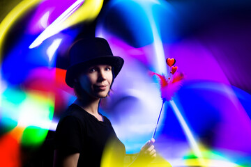 Woman magician in a black hat against a background of multi-colored light. Magic, sorcery,...