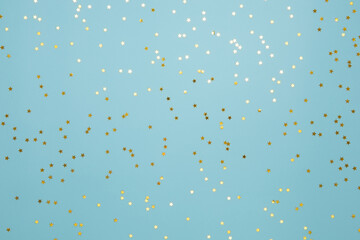 Fototapeta na wymiar Star shaped shining golden confetti on light blue background. Sparkle sequins. Festive design