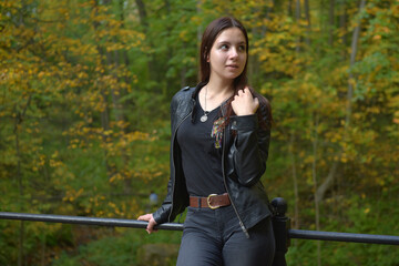 girl in a black leather jacket and black jeans in an autumn park