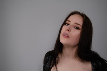 Naklejka premium young brunette woman in black leather jacket exhales white smoke. beautiful girl millenial on grey background smoking. bad habit
